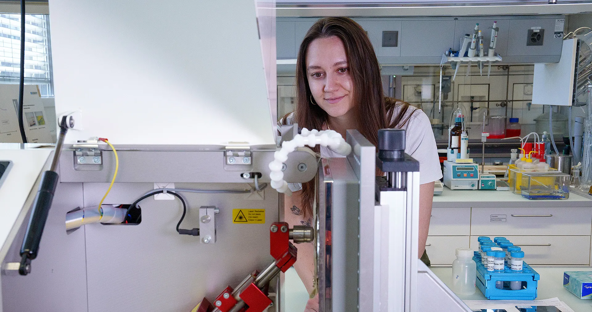 At the Materials Laboratory at the headquarters in Rapperswil-Jona (CH), chemist Jasmin Krummenacher tests the surface durability of an actuator plate. A robot arm with an artificial finger presses the buttons 20,000 times. (Photo)