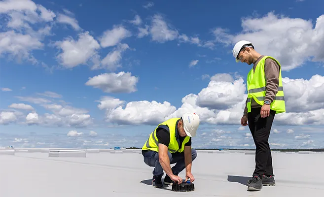 Installing of the roof drainage system Geberit Pluvia by two workers wearing yellow vests.&nbsp; (Photo)